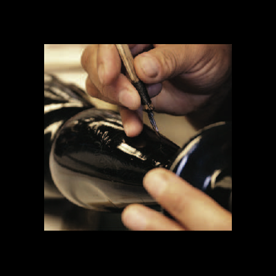 Pessoa pintando sapato de couro preto com pincel fino