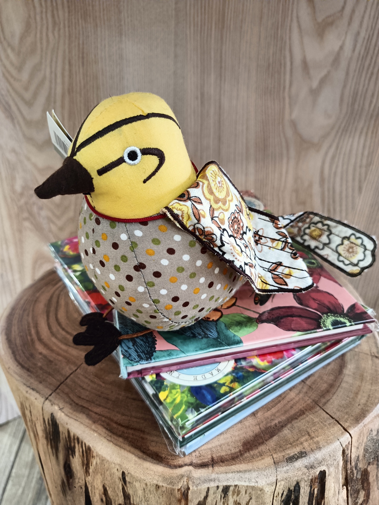 Pisa-Papéis Yellow Hammer - Passarinho Pássaro de peluche colorido em cima de cadernos florais sobre madeira