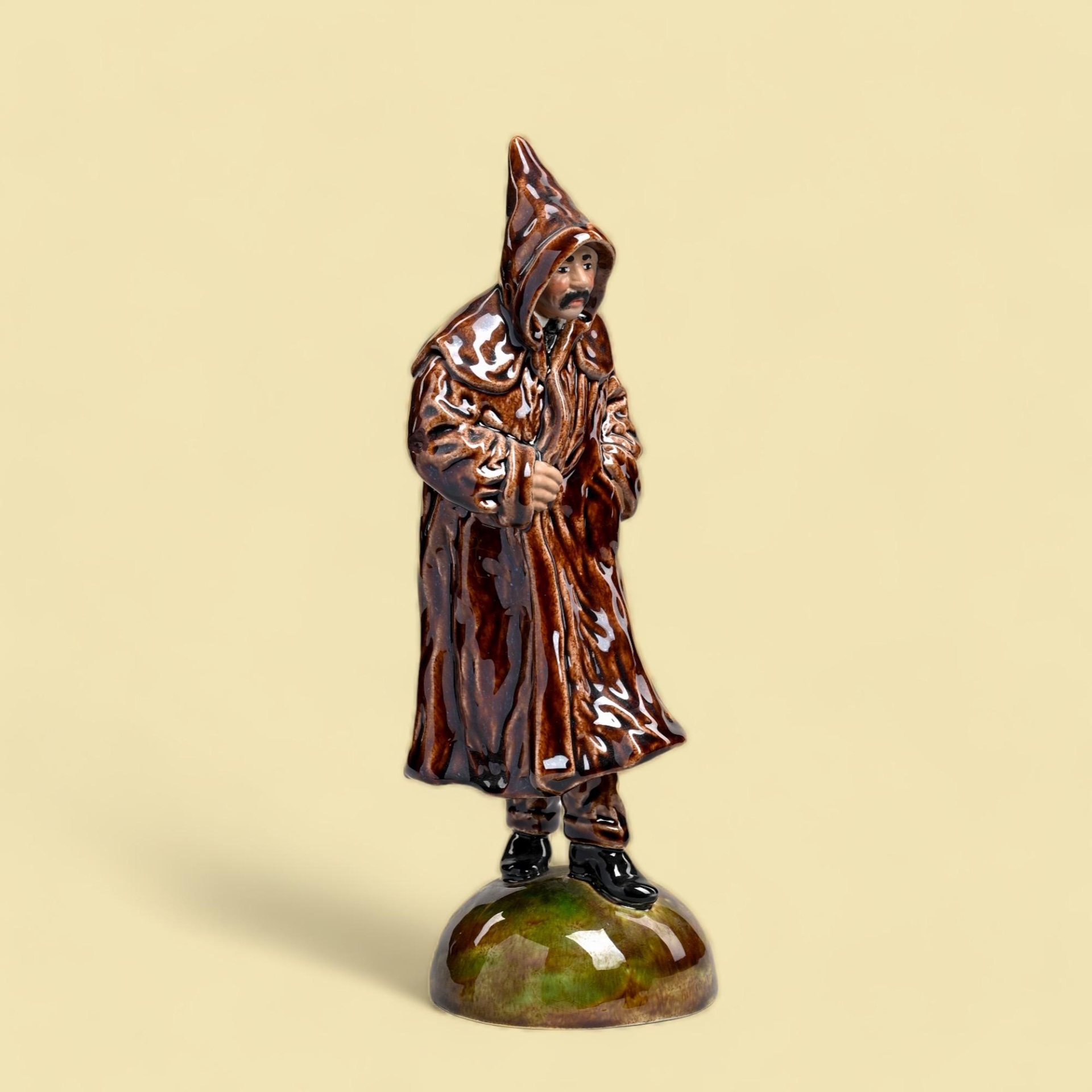 Bordallo Pinheiro - Figuras de Movimento o Gabão Figura cerâmica de homem com capa e capuz castanhos em base verde e castanha