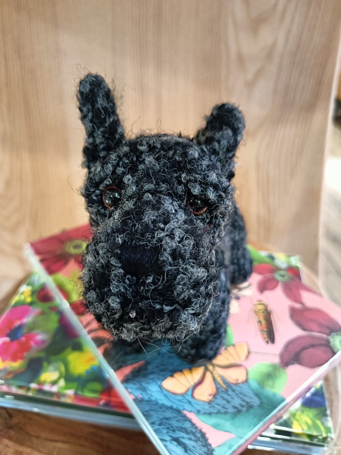 Pisa-Papéis Mac Scottie - Terrier Pelúcia de cão preto feita de fio felpudo sobre cadernos coloridos com padrões florais