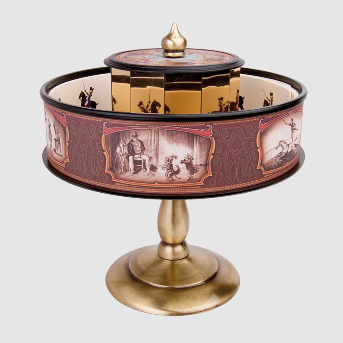Praxinoscopio Classico pe de latão Produto metálico dourado com decoração circular e ilustrações em tons castanhos e creme.