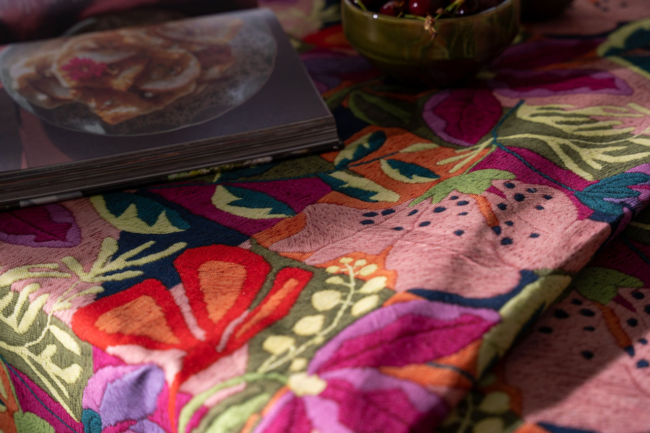 Toalha de Mesa 100% Algodão Flores KIRIKU - Tessitura Toalha de mesa com padrão floral colorido e objetos em cima