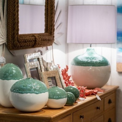 Objetos decorativos em cerâmica verde e branca sobre móvel de madeira com molduras e espelho