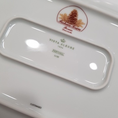 Parte de prato de porcelana branco com marcas e logótipos no verso