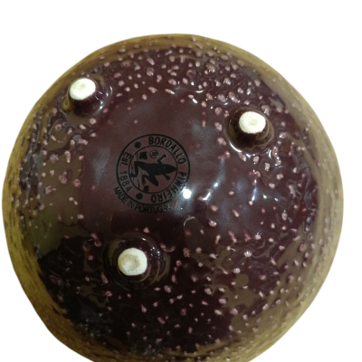 Taça de cerâmica castanha e roxa com base trípode e estampagem da marca.