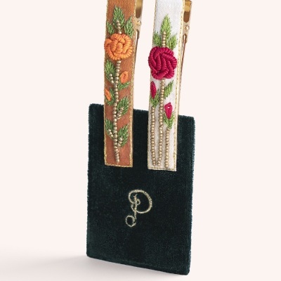 Grampos de cabelo florais bordados com contas sobre suporte preto com letra D