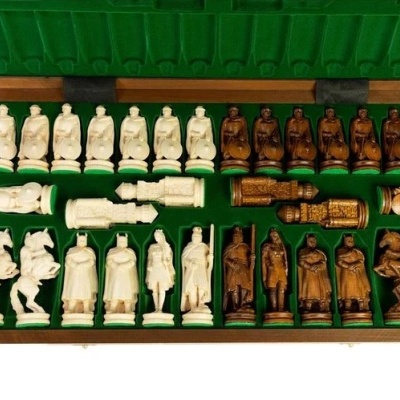 Peças de xadrez em creme e castanho numa caixa verde forrada a tecido