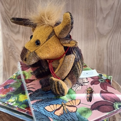 Boneco de tecido animal sobre capas coloridas com padrão floral e borboletas