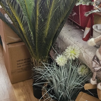 Plantas artificiais em vasos com folhas e flores junto a caixas e decoração de Natal.