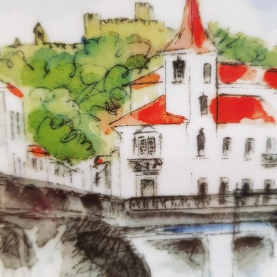 Azulejo decorativo pintado com vila, casas brancas, telhados vermelhos e castelo ao fundo