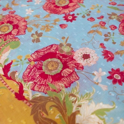 Tecido com padrão floral colorido em fundo azul e detalhes decorativos.