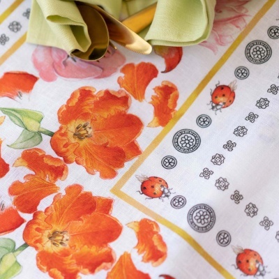 Toalha de mesa floral laranja com detalhes circulares e joaninhas, guardanapo verde e talheres prateados