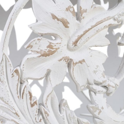 Detalhe de peça decorativa de metal branco envelhecido com padrão floral e folhas