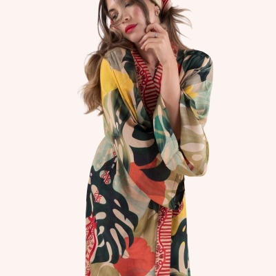 Mulher com vestido colorido de padrão floral e folhas, com lenço na cabeça combinando