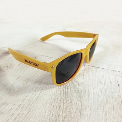 Óculos de sol amarelos com lentes escuras sobre superfície branca