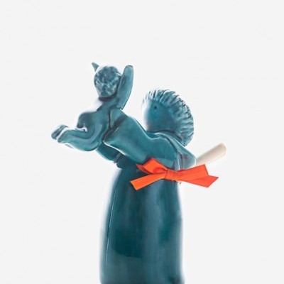 Escultura cerâmica azul com figura humana e criança, com pergaminho e laço laranja