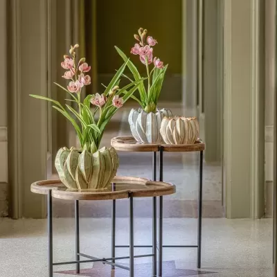 Vasos cerâmicos com flores artificiais em mesas redondas de madeira e metal