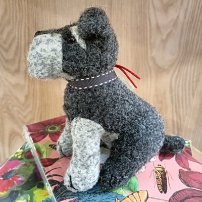 Pelúcia de cão cinzento e branco com coleira preta sobre caixas coloridas