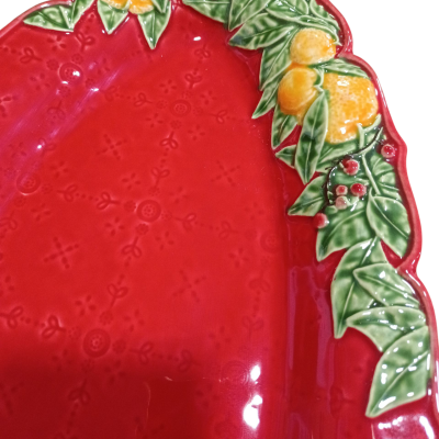 Prato oval vermelho com relevo e borda decorada com folhas e frutos amarelos e vermelhos