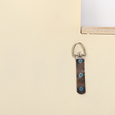 Parte traseira de um quadro com suporte metálico e fita castanha para pendurar