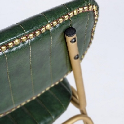 Cadeira verde escura em pele com tachas douradas e estrutura metálica bege