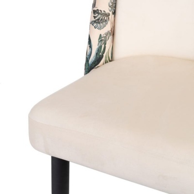 Detalhe de cadeira com assento creme e encosto com padrão de folhas verdes