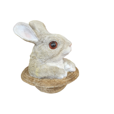 Estátua de coelho cinzento grande sentado num chapéu de palha