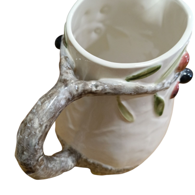 Caneca de cerâmica com pega em forma de ramo e decoração de folhas e frutos