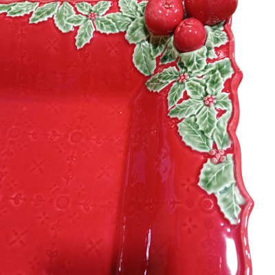 Prato decorativo vermelho com folhas verdes e frutos vermelhos no canto