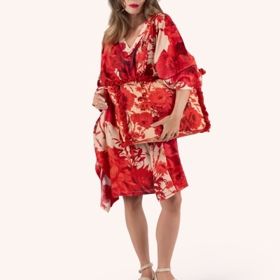 Mulher com vestido floral vermelho e bege, mala combinando e sapatos plataforma bege em fundo branco.