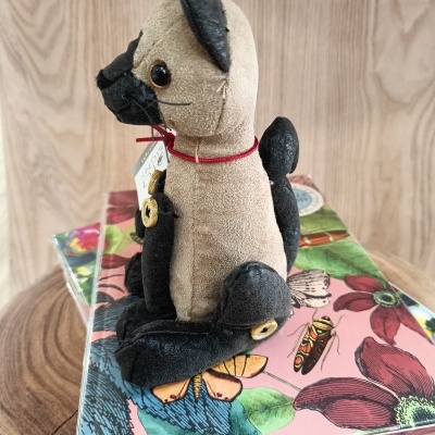 Boneco de peluche de cão com detalhes pretos sentado sobre agendas floridas sobre madeira