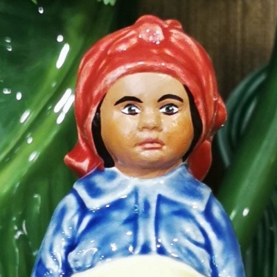 Figura decorativa em cerâmica de pessoa com lenço vermelho e camisa azul