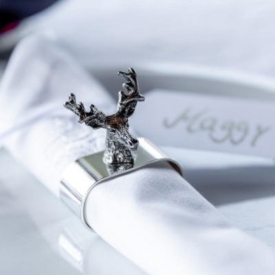 Guardanapo branco com suporte metálico prateado e figura de rena