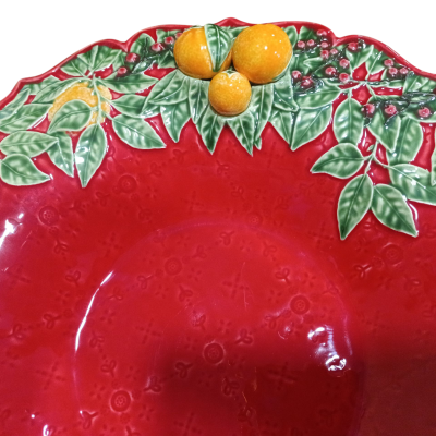 Prato decorativo vermelho com borda de folhas verdes, bagas vermelhas e limões amarelos.