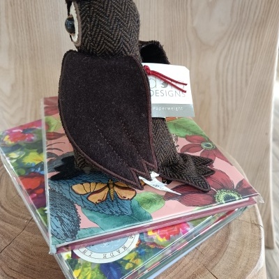 Coruja de tecido castanho sobre cadernos com capas florais