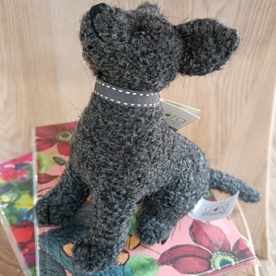 Cão decorativo tecido cinzento escuro sentado sobre caixas florais