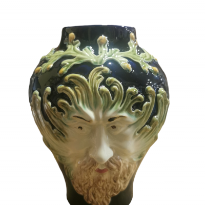 Jarro cerâmico com rosto humano e detalhes em relevo de folhas verdes.