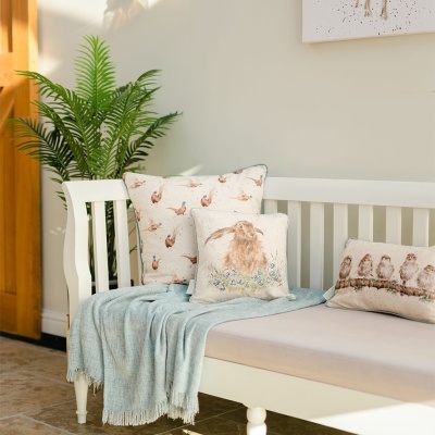 Banco branco com almofadas decorativas de coelhos e cobertor azul claro