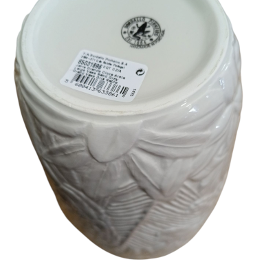 Vaso de cerâmica branco com textura floral e folhas e etiqueta com código de barras.