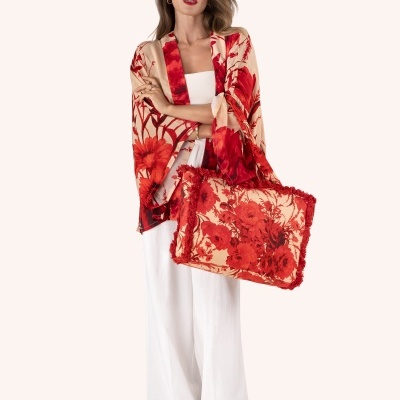 Mulher com roupa branca e xale com padrão floral vermelho a combinar com bolsa floral