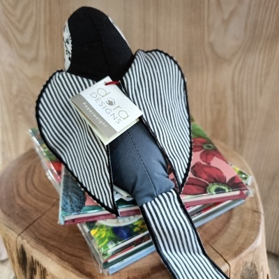 Boneco decorativo em tecido com padrões listrados e cor azul sobre livros coloridos num tronco de madeira