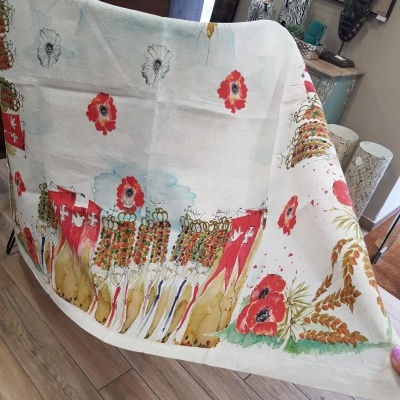 Toalha branca com flores vermelhas e figuras humanas estilizadas coloridas