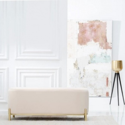Banco estofado bege claro com base dourada em sala branca com painel abstrato
