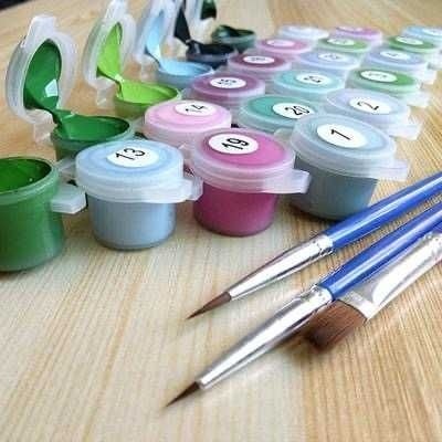 Conjunto de tintas coloridas numeradas com pincéis sobre mesa de madeira