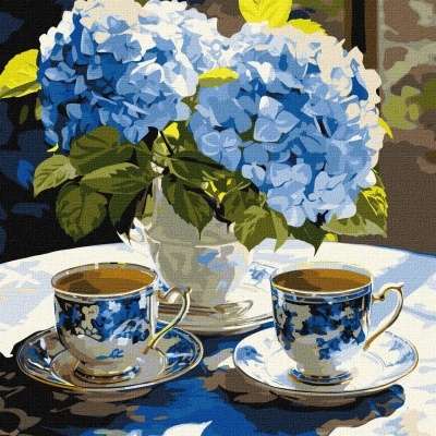 Chávenas de chá azuis e brancas com vaso de flores azuis e folhas verdes numa mesa