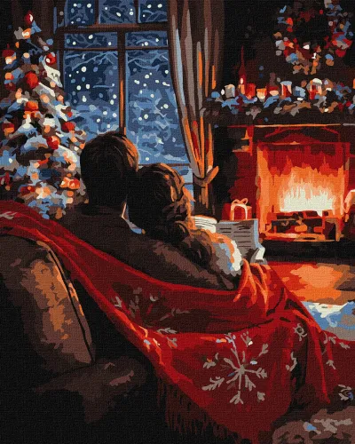 Casal sentado no sofá com manta vermelha junto a lareira acesa e decoração de Natal
