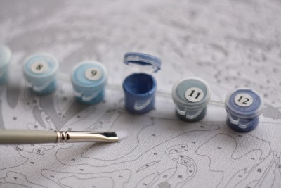 Recipientes de tinta azul numerados e pincel sobre tela para pintar por números