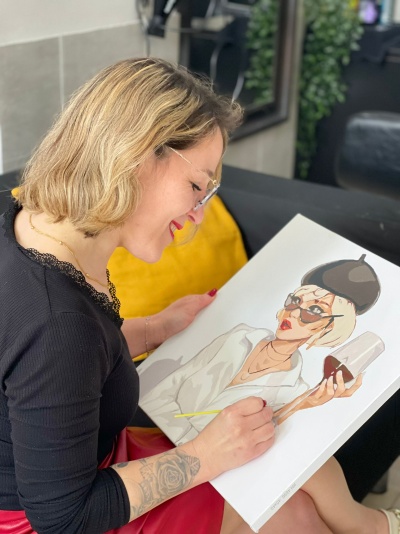 Mulher a pintar ilustração feminina numa tela com cores claras e detalhes em preto e vinho