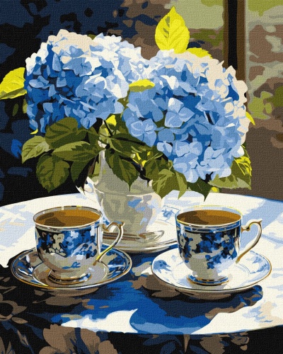 Chávenas de chá azuis e brancas com vaso de flores azuis e folhas verdes numa mesa