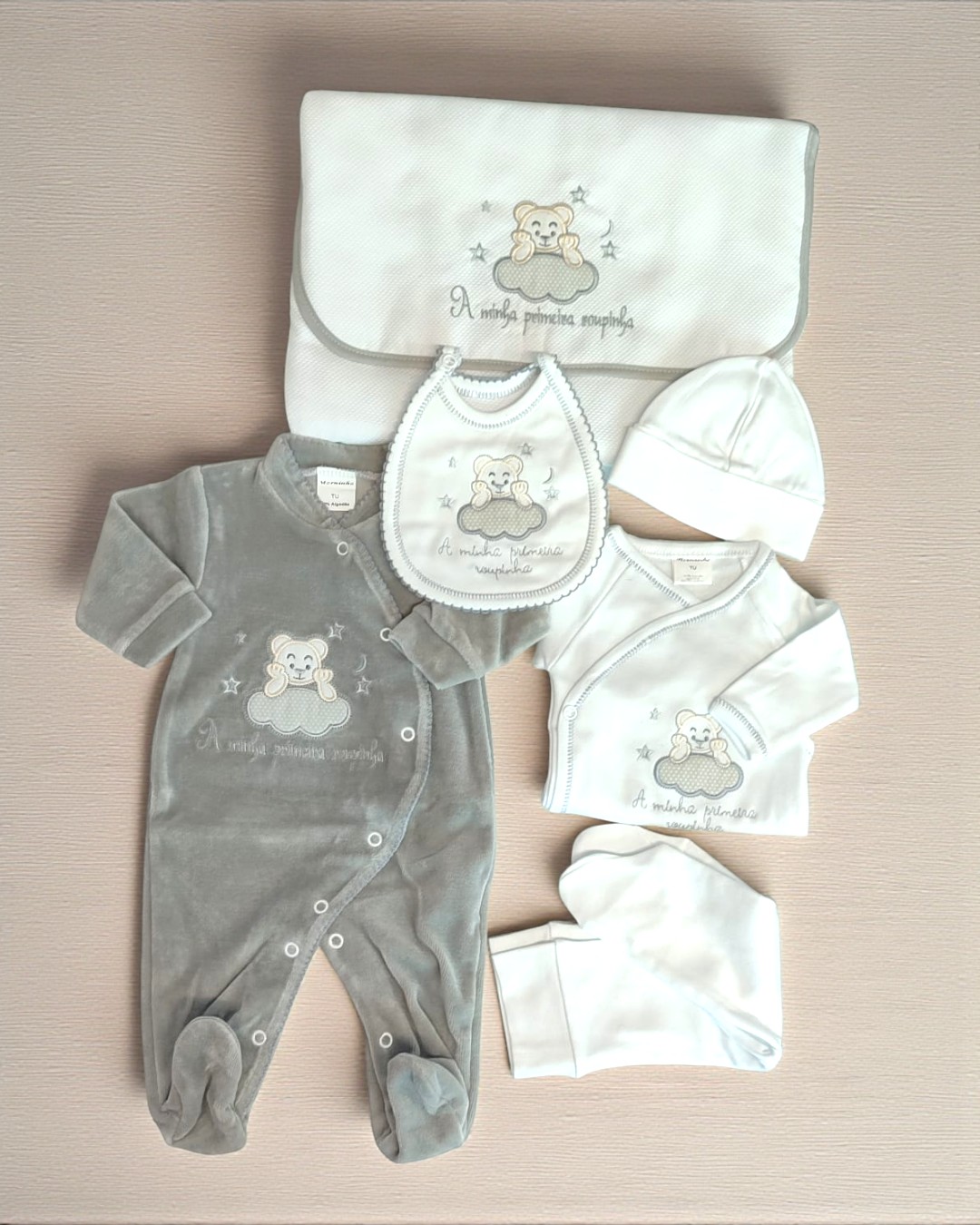 Conjunto de roupa de bebé com ursinho bordado e frase em branco e cinzento.